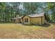 A ranch style home with beige siding and brown trim surrounded by mature trees, featuring a concrete patio and well-kept lawn at 225 Hardwood Dr, Covington, GA 30016