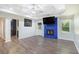Bright living room featuring a blue brick fireplace, modern ceiling fan, and gray wood flooring at 225 Hardwood Dr, Covington, GA 30016