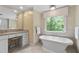 Bathroom featuring soaking tub, granite vanity, and serene backyard view at 5049 Lake Ter, Marietta, GA 30068