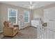 Bedroom with a white crib, dresser, rocking chair, two large windows, and soft neutral colors at 812 Roget Way, Lawrenceville, GA 30045