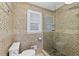 Shower with decorative tilework, a glass door, and a shuttered window above the toilet at 1005 Cromwell Cv, Snellville, GA 30078