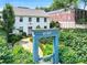Elegant white home framed by lush greenery and a neighborhood welcome gate at 67 Delmont Ne Dr, Atlanta, GA 30305