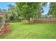 Large, fenced backyard with mature trees, manicured lawn, and mulch beds at 3880 Admiral Dr, Chamblee, GA 30341