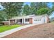Charming brick home with a white garage, front porch, well-manicured lawn, and a long driveway at 3880 Admiral Dr, Chamblee, GA 30341