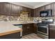 Kitchen boasts stainless steel appliances, dark wood cabinets, decorative tile backsplash, and an eating area at 163 Silver Fox Trail Trl, Dallas, GA 30157