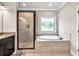 Modern bathroom with a glass enclosed shower and a soaking tub below a window at 2980 Beards Rd, Buford, GA 30518