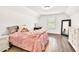 Bright bedroom featuring hardwood floors, soft pink bedding, a full-length mirror, and a small work area at 2980 Beards Rd, Buford, GA 30518