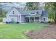 Well-maintained front yard features a plush green lawn, colorful hydrangeas, and a charming porch with stone detailing at 2980 Beards Rd, Buford, GA 30518