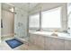 Bright bathroom showcasing a glass-enclosed shower and a luxurious soaking tub under a large window at 3060 Mccannon Mill Dr, Dacula, GA 30019