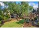 Backyard view featuring a playground, deck, mature trees, and a well-maintained lawn at 2517 Stone Manor Dr, Buford, GA 30519
