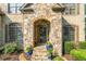 Close-up of home's stone entrance with arched doorway and blooming landscaping at 2517 Stone Manor Dr, Buford, GA 30519