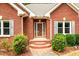 Close-up of the brick home's front entrance, highlighting a glass door and manicured landscaping at 3648 Clark Hill Way, Buford, GA 30519