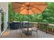Outdoor deck featuring a patio table and chairs, grill, umbrella, and wooded scenery at 124 Hunters Mill Rd, Woodstock, GA 30188