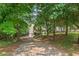 Home's exterior with a long driveway, three-car garage, and mature trees at 124 Hunters Mill Rd, Woodstock, GA 30188