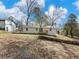 View of a grassy backyard of a single-story home under a blue partly cloudy sky at 1783 Big Valley Ln, Stone Mountain, GA 30083