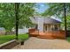 Backyard view featuring home's deck, patio, and landscaping with mature trees at 12290 Greenmont Walk, Alpharetta, GA 30009