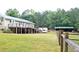 Home's back elevation, deck, grassy backyard, and large storage shed in a wooded, green setting at 3129 Etchison Rd, Loganville, GA 30052