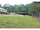 Overview of the extensive backyard featuring the home, fencing, and storage shed in a wooded, green setting at 3129 Etchison Rd, Loganville, GA 30052