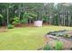 Landscaped backyard featuring mature trees, garden boxes and small shed at 3129 Etchison Rd, Loganville, GA 30052