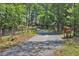 Scenic paved driveway leading through wooded property, featuring a mailbox stand, fencing, and a gated entrance at 3129 Etchison Rd, Loganville, GA 30052