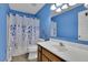 Bright bathroom with blue walls, patterned shower curtain, and wood vanity at 3202 Ivy Station Way, Duluth, GA 30096