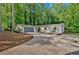 Charming single-story home featuring a gray garage, driveway, wooden door, and lush, mature trees surrounding the property at 4492 Riverwood Cir, Decatur, GA 30035