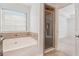 Bright bathroom with jetted tub, tiled accents, glass enclosed shower and access to bedroom at 55 Bowen Ave, Atlanta, GA 30315
