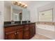 Bathroom featuring a double vanity with dark cabinets, granite countertops, and a soaking tub at 55 Bowen Ave, Atlanta, GA 30315
