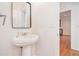 Bright half bathroom featuring a pedestal sink, stylish mirror, and views into the adjacent kitchen at 55 Bowen Ave, Atlanta, GA 30315