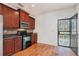 Kitchen featuring wood cabinets, tile backsplash, black appliances, and hardwood flooring at 55 Bowen Ave, Atlanta, GA 30315