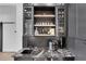 Elegant wet bar featuring dark cabinetry, a marble countertop, and stylish glass shelving at 13 Highland Park Ne Ln, Atlanta, GA 30306