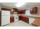 Functional kitchen with white appliances, tile flooring, and dark wood cabinets at 134 Timber Creek Sw Ln, Marietta, GA 30060