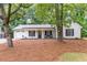 Charming, single-story home with white brick, black shutters, rocking chairs, and manicured landscaping at 2038 Summertown Dr, Norcross, GA 30071