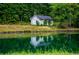 Scenic view of the pond reflecting the house in the water surrounded by lush greenery and tall trees at 300 Old Boy Scout Rd, Whitesburg, GA 30185