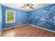 Unique bedroom with blue textured walls, hardwood floors, and a view to the outside, offering a distinct style at 129 Bill Smith Dr, Canton, GA 30114