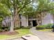 Inviting condo exterior featuring mature trees, lush landscaping, and a charming walkway to the front door at 3915 Woodridge Way, Tucker, GA 30084