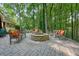 Backyard patio with stone fire pit and ample seating surrounded by trees at 11940 Mountain Laurel Dr, Roswell, GA 30075