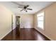 An empty bedroom with a ceiling fan, light walls, dark floors, and a window allowing for natural light at 3220 Memorial Dr, Decatur, GA 30032