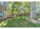 Green backyard with a mature tree and wooden deck, ideal for outdoor activities and enjoying nature at 3830 Gallant Fox Ct, Duluth, GA 30096