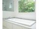 Modern bathroom featuring a soaking tub, large window with natural light, and granite countertops at 265 Landfall Rd, Atlanta, GA 30328