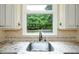 Close up of a kitchen sink with granite countertops and a view of the backyard at 265 Landfall Rd, Atlanta, GA 30328
