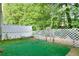 A small, fenced backyard area with a green surface, surrounded by a white fence and trees at 5640 Terremont Cir, Norcross, GA 30093