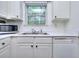 A view of a kitchen featuring white cabinets, double sinks, stainless faucet, and dishwasher at 5640 Terremont Cir, Norcross, GA 30093