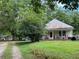 Exterior view of a quaint single-story home with a weathered tin roof and mature shade trees at 7000 Petersburg Rd, Fairburn, GA 30213