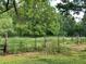 Picturesque acreage featuring a meadow with lush vegetation, framed by mature trees and a rustic fence at 7000 Petersburg Rd, Fairburn, GA 30213