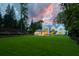 Backyard showcasing a manicured lawn, sparkling pool, and elegant outdoor living spaces at dusk at 258 Pineland Nw Rd, Atlanta, GA 30342