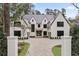 Beautiful two-story white home featuring dark trim, elegant landscaping, and a circular driveway at 258 Pineland Nw Rd, Atlanta, GA 30342