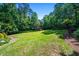 A large grassy backyard with mature trees, mulch, and meticulously maintained landscaping at 1385 Northcliff Trce, Roswell, GA 30076
