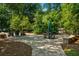 Stone patio with furniture and play set is surrounded by lush greenery for a relaxing outdoor space at 1385 Northcliff Trce, Roswell, GA 30076