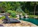 Relaxing lounge chairs by a backyard pool with waterfall feature surrounded by tropical foliage at 1385 Northcliff Trce, Roswell, GA 30076